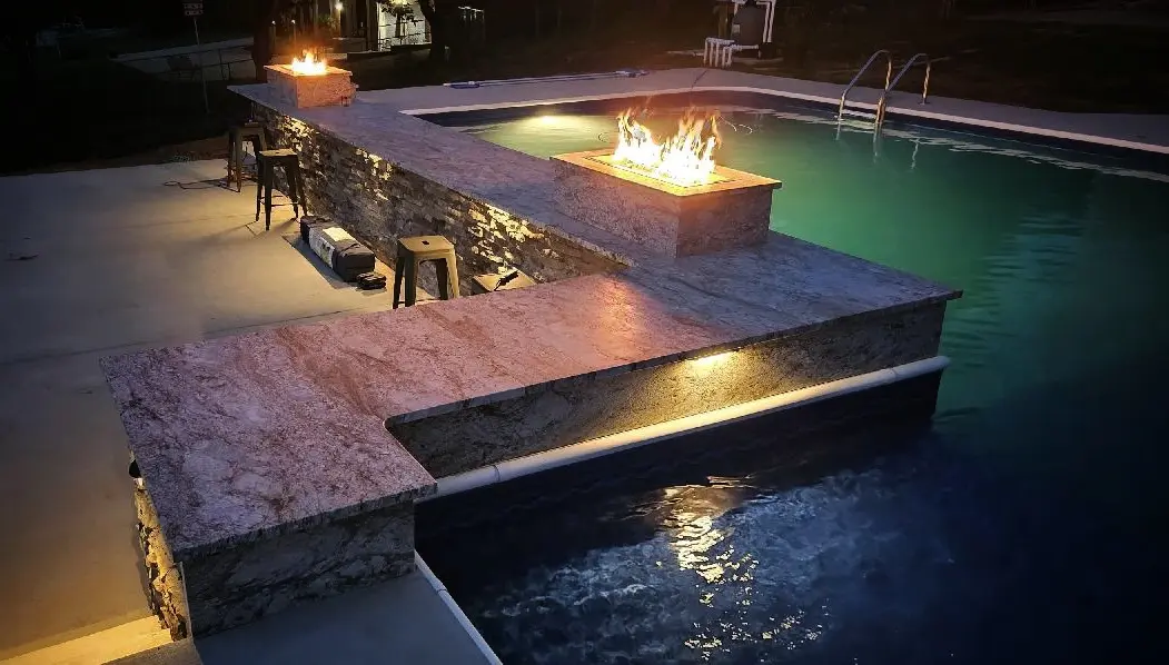 A fire pit sitting next to the pool at night.
