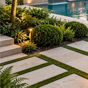 Concrete pavers set in grass lead to stone steps next to a landscaped garden and a swimming pool.