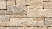 A wall constructed of rectangular, tan and gray stones.