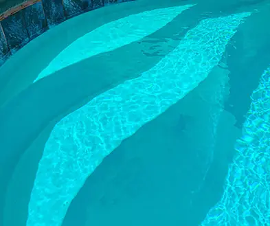 Steps leading into a swimming pool with bright blue water.
