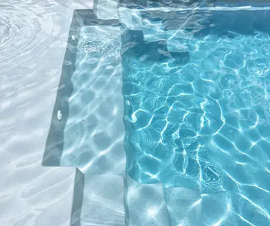 A swimming pool with shallow steps leading into clear, blue water.