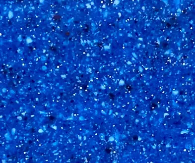 A blue surface with a speckled, multi-colored pattern of small light and dark flecks.