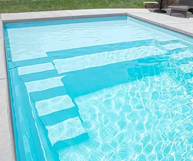 A backyard swimming pool with built-in stairs leading into the water.