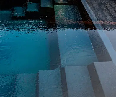 Steps leading into a dark blue swimming pool.