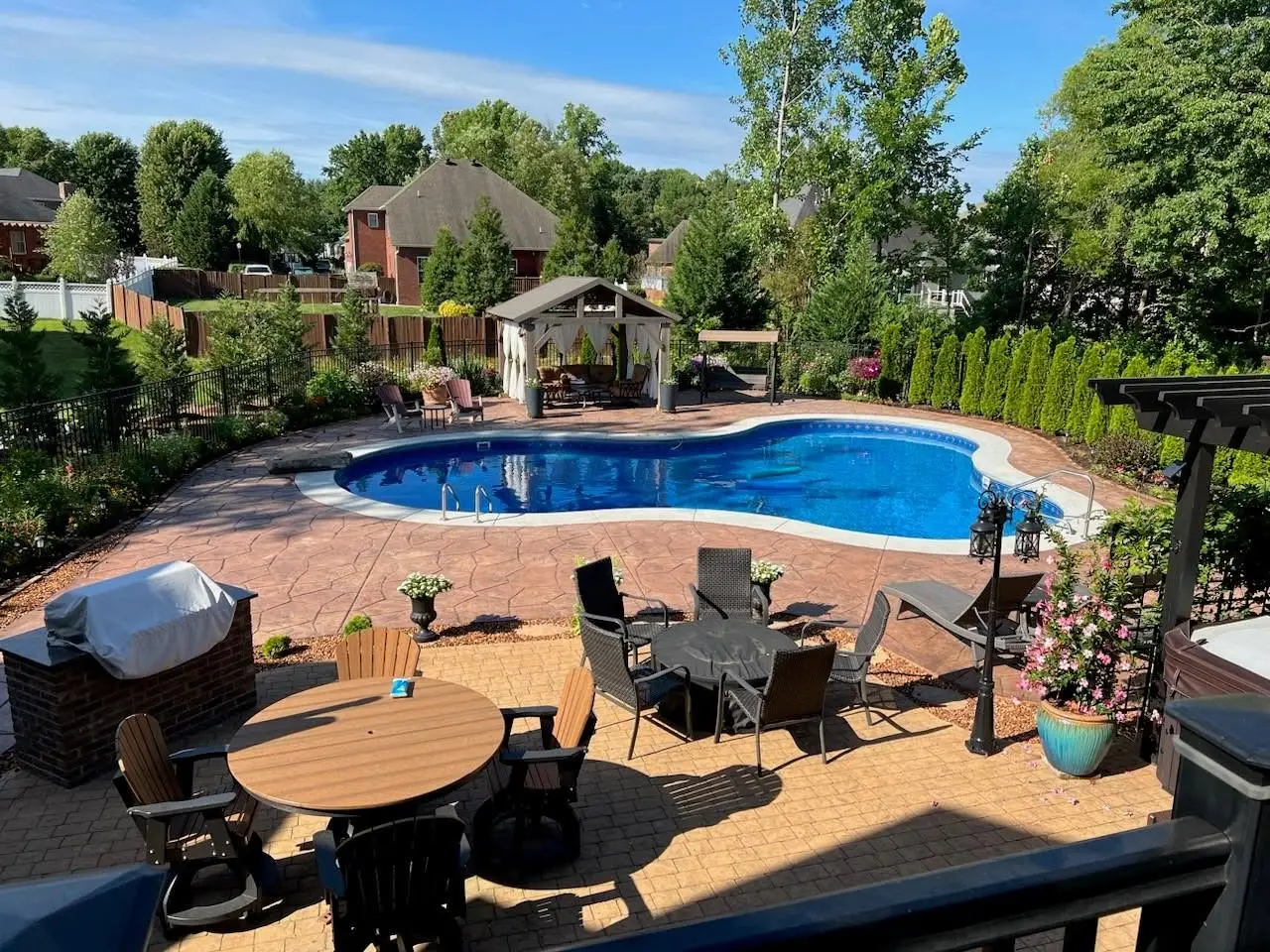 Inground pool with a curved shape, patio, and outdoor seating